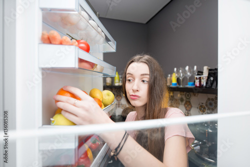 Woman taking food from the refrigerator. View from the inside