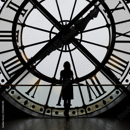 Woman silhouette standing in front of large clock photo
