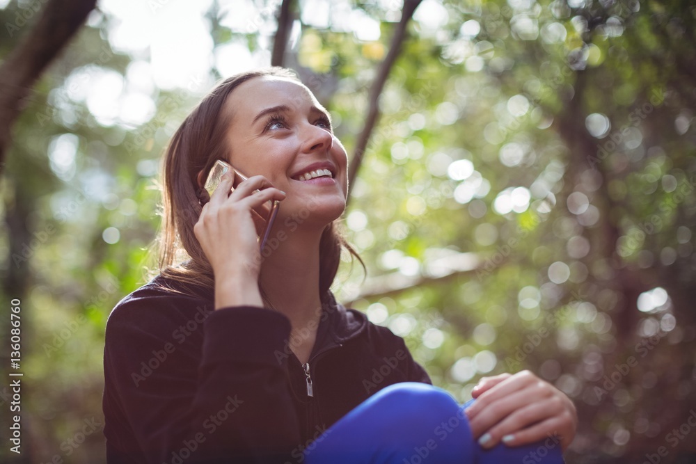 Woman talking on smartphone while sitting in forest Woman talking on smartphone while sitting in forest