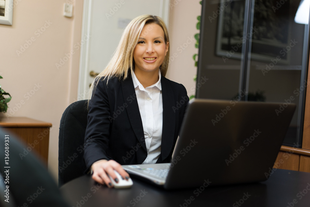 Portrait of a young smiling businesswoman using her computer Portrait of a young smiling businesswoman using her computer