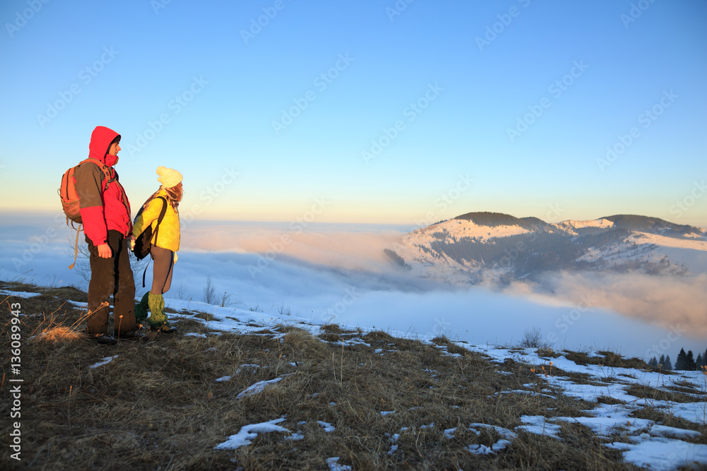 Obraz premium Young couple hiking outdoors with backpacks in winter mountains