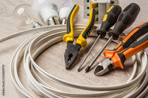 set of electrician tools, a coil of wire and equipment in backgr photo