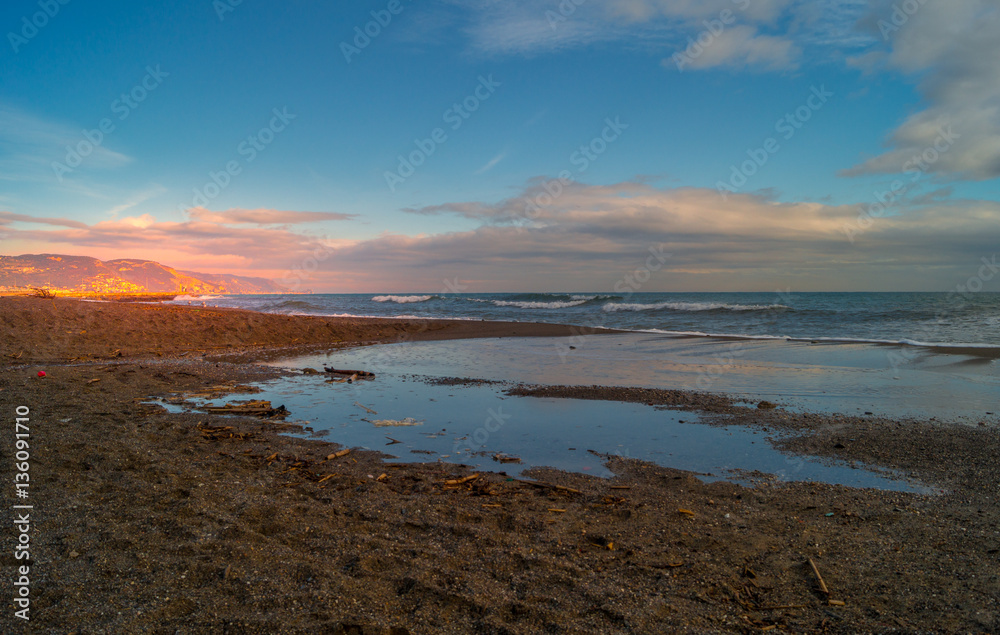 Sunset on beach. sea landscape, wirh red sky and clouds. Beach with waves and rocks, 