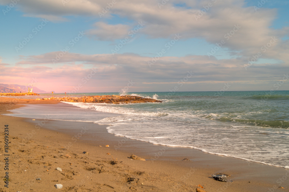 Sunset on beach. sea landscape, wirh red sky and clouds. Beach with waves and rocks, 