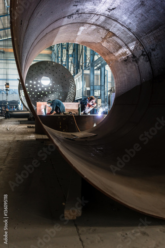 Two workers welding in a factory manufacturing boilers © Kzenon