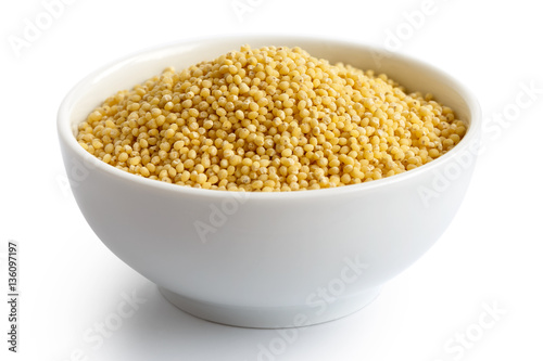 Dry millet in white ceramic bowl isolated on white.