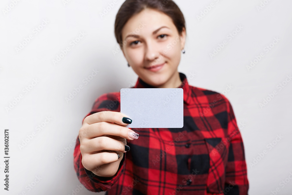 Selective focus. Portrait of female businesswoman in checked red shirt holding a parchment business card with copy space for your text or advertising content isolated over white background Selective focus. Portrait of female businesswoman in checked red shirt holding a parchment business card with copy space for your text or advertising content isolated over white background