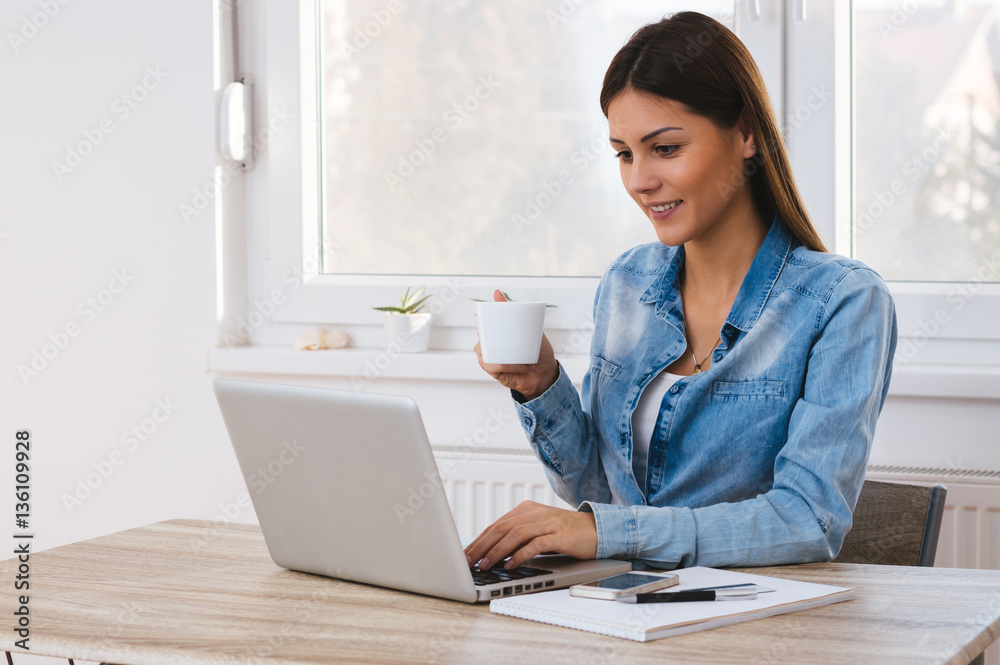 Young smiling woman at desk networking, drinking coffee Young smiling woman at desk networking, drinking coffee