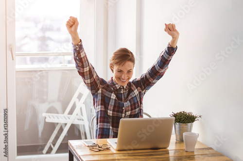 Professional young woman receiving good news on her laptop in of