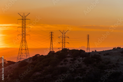 Los Angeles skyline at sunset viewed from afar through power lines.