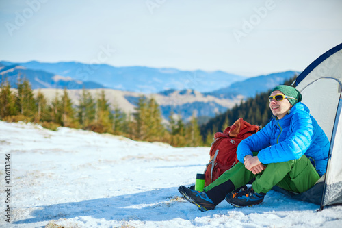 hiker resting near the tent in the Carpathians mountains at winter