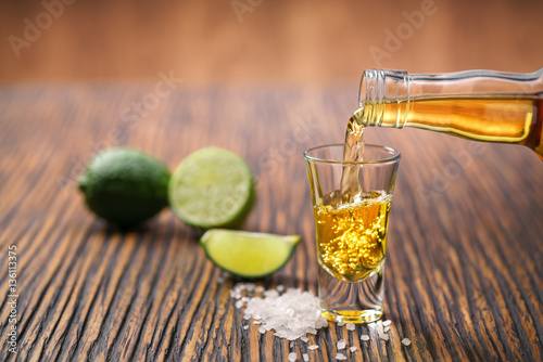 Pouring  gold tequila shot with lime