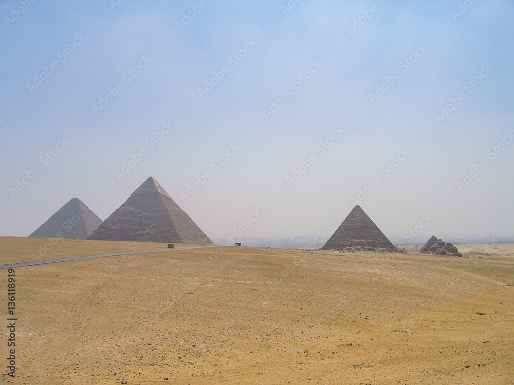 Many tour buses and cars driving on road through great pyramids Many tour buses and cars driving on road through great pyramids