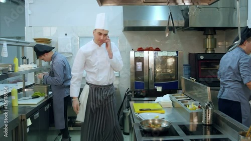 Chef taking pan out of the oven and answering the phone call