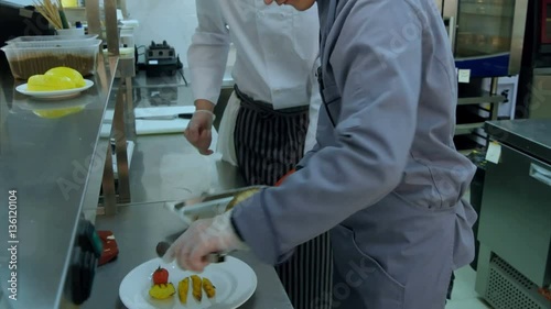 Cook trainee learning to serve vegetables on a plate photo