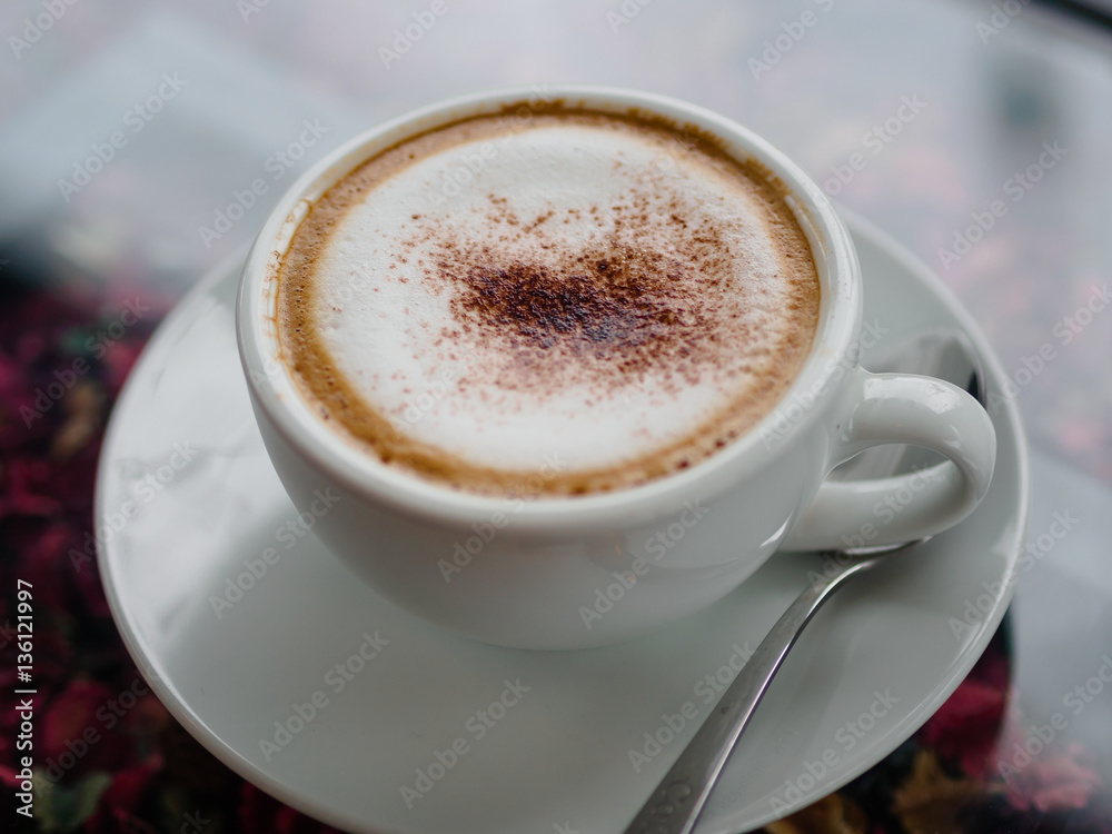 Obraz premium cappuccino coffee on white cut and on glass table with blur background