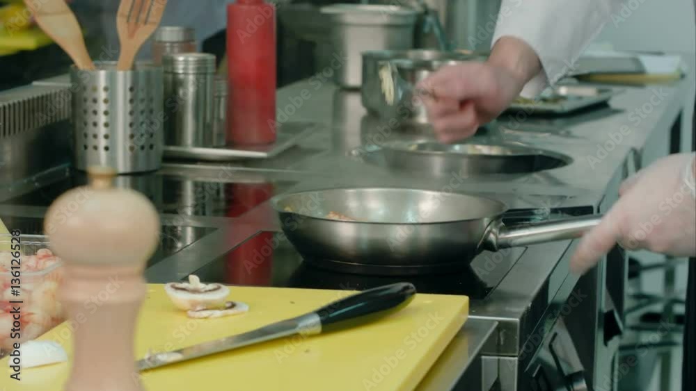 Male chef tossing shrimps in a frying pan Male chef tossing shrimps in a frying pan