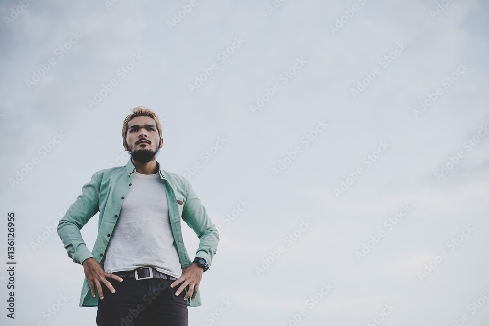 Young hipster man standing in the park with sky looking away. Young hipster man standing in the park with sky looking away.