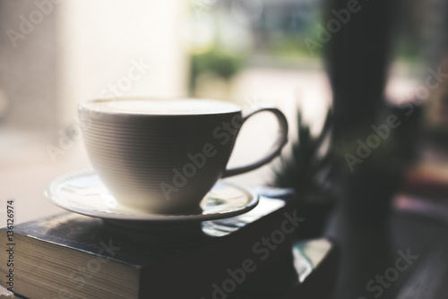 Vintage color Cup of coffee with book in coffee shop.