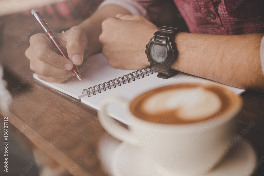 A coffee cup on wood bar beside window in cafe with hipster man