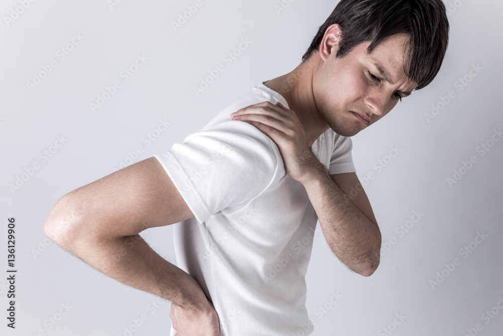 young man having horribly stiff shoulders young man having horribly stiff shoulders