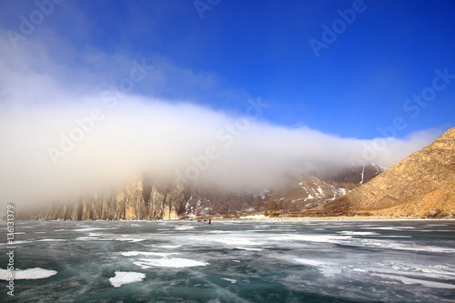 Rocky shore of lake Baikal in the fog in winter Rocky headland on the Western coast of lake Baikal sticks in ice-covered body of water, Fog hampers visibility