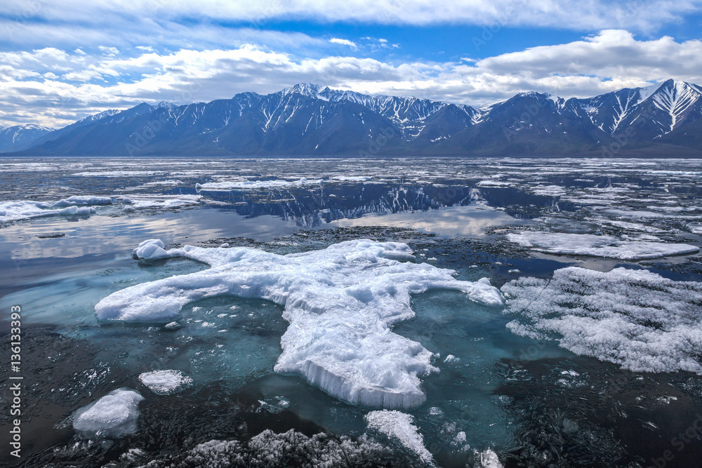 Big ice floe with blue underwater foundation, spring landscape