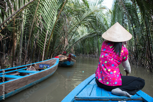 Obraz na płótnie Young Woman paddling along the Mekong River in Vietnam