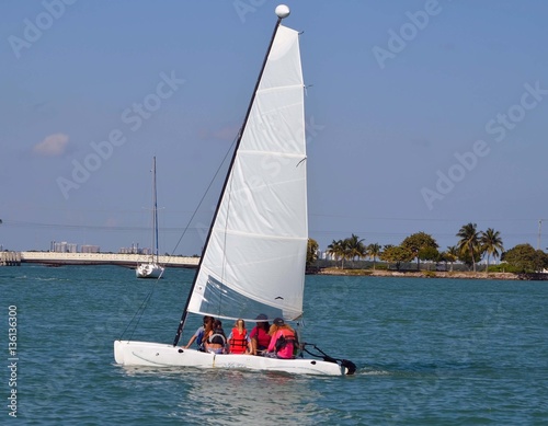 Four teen agers and one adult enjoying a saturday afternoon cruise on a small sailing catamaran on the florida intra-coastal waterway near miami beach.