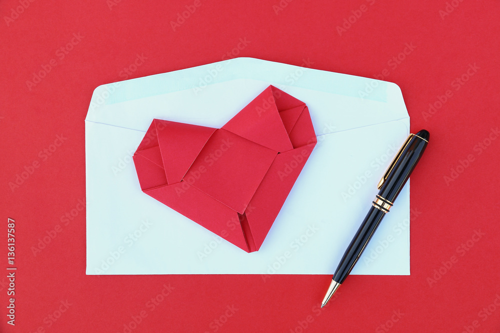 folding red paper heart on white envelope and black business pen folding red paper heart on white envelope and black business pen