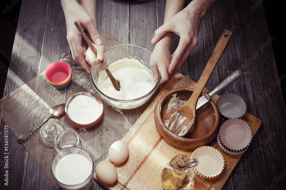 Little girl and her mother cook dough for home-made cupcakes. Little girl and her mother cook dough for home-made cupcakes.