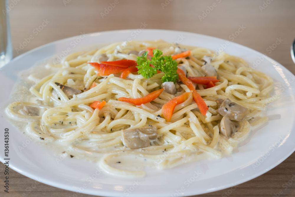 White sauce and mushroom spaghetti with decorated with red sweet pepper and parsley in the close up view