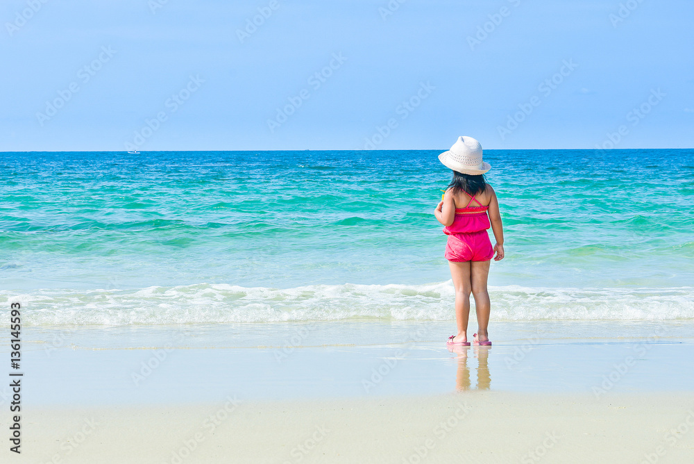 Happy child enjoying beach relaxing joyful in summer by tropical blue water. Beautiful bikini model happy on travel wearing beach sun hat on Thailand
