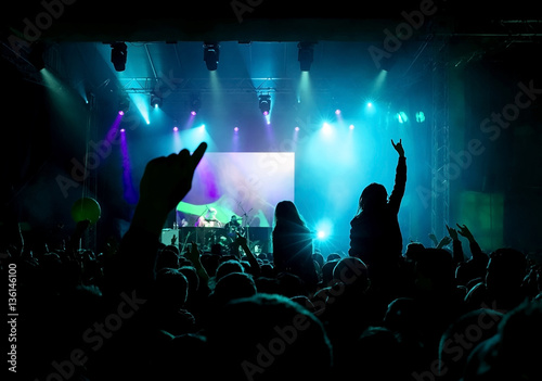 Rock concert  silhouettes of happy people raising up hands