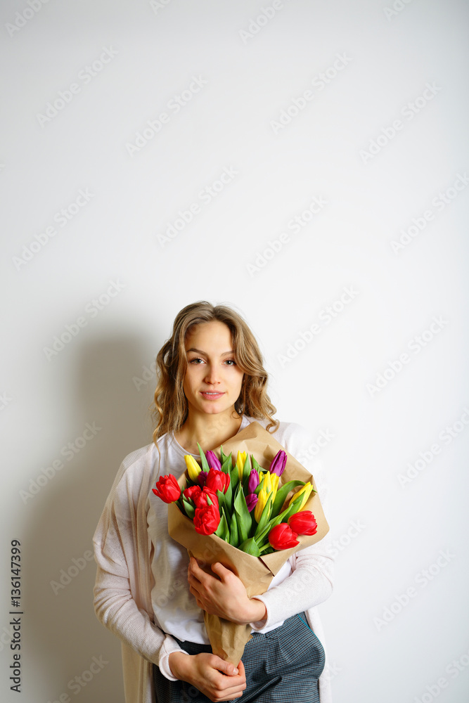 Feminine woman is standing with a bouquet of beautiful tulips. L Feminine woman is standing with a bouquet of beautiful tulips. L