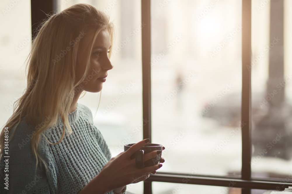 Woman in pullover sitting with cup of coffee in a cafe Woman in pullover sitting with cup of coffee in a cafe