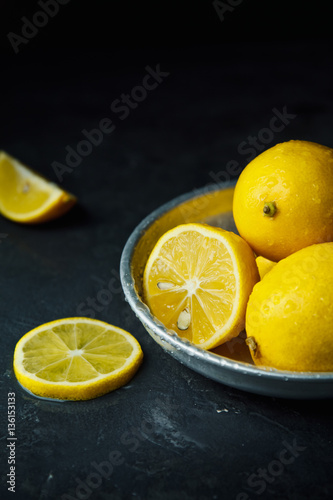 Beautiful ripe lemons in plate on a black background