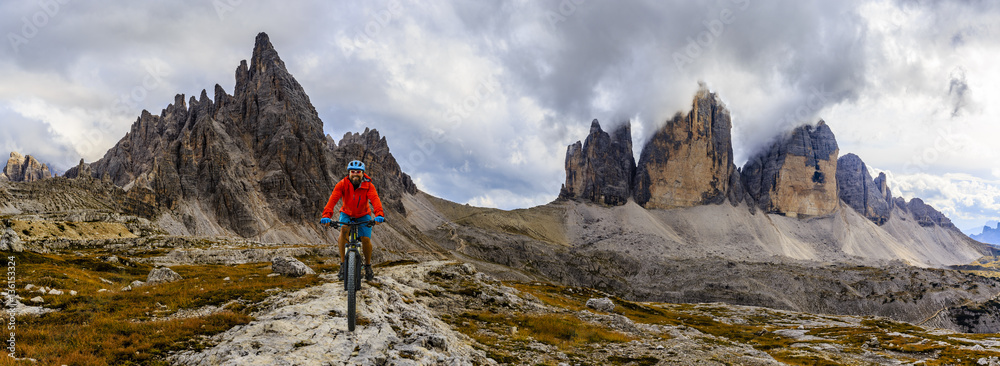 View of cyclist riding mountain bike on trail in Dolomites,