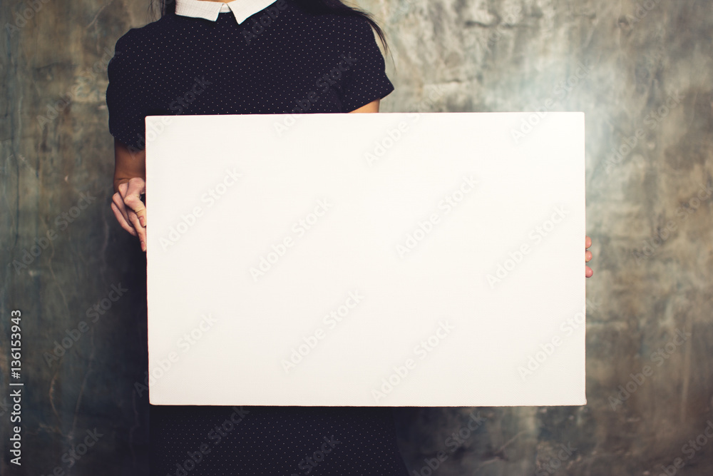 Girl in dress posing with white canvas. Horizontal mockup - obrazy, fototapety, plakaty 
