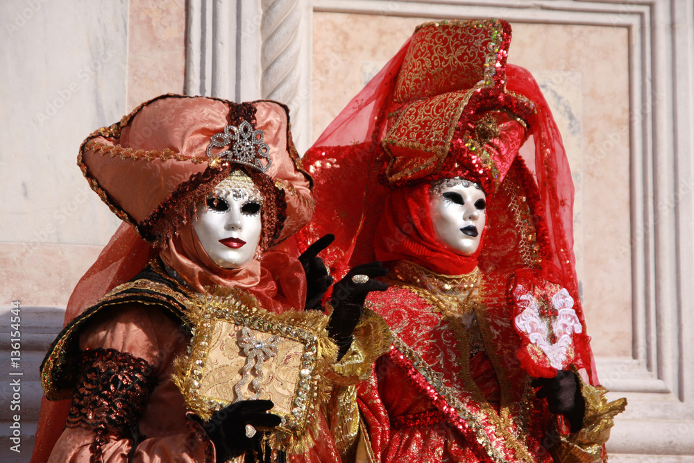 Women in colorful costumes and masks posing at the Venice carnival in Italy