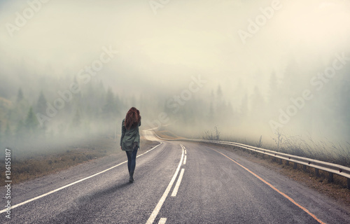 girl walking alone on mountain highway in winter foggy day