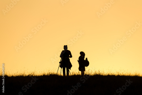 silhouette of photographer taking top on mountain with sunset.