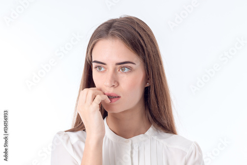 young serious girl bitten fingers and thinking isolated on white background