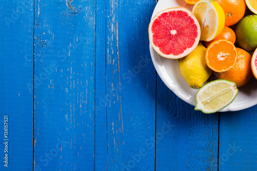 various types of citrus fruit on a blue painted wooden background