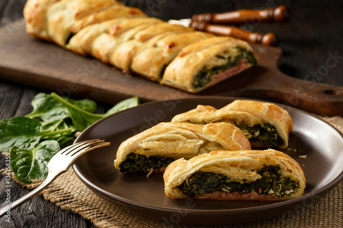 Fotografie Homemade puff pastry pie with spinach, ham and cheese.