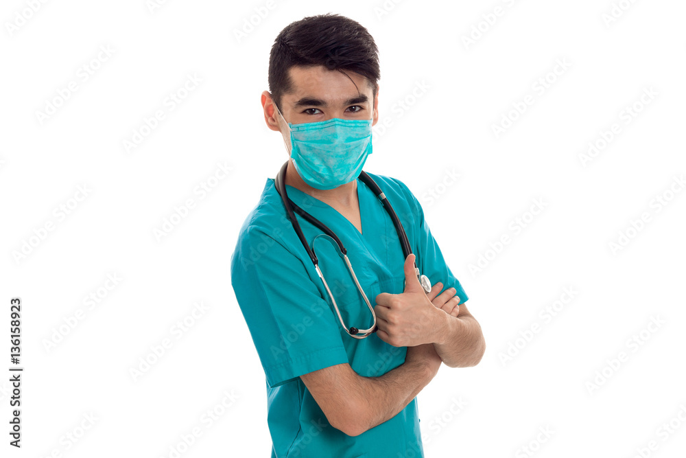 handsome man doctor posing in uniform and mask isolated on white background in studio handsome man doctor posing in uniform and mask isolated on white background in studio
