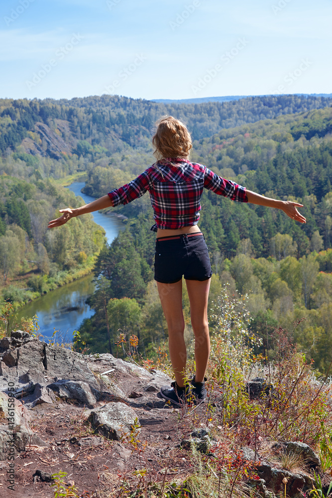Young blonde woman tourist   on a cliff over the river Berd