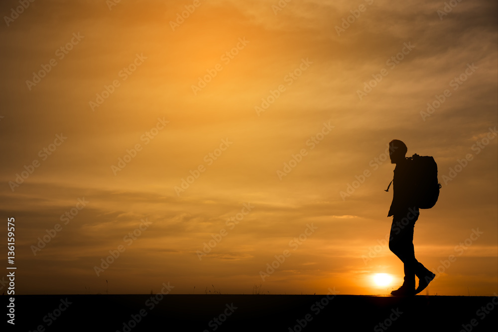 Silhouette of  backpacker  who were traveling.The background image is a sunset in Thailand