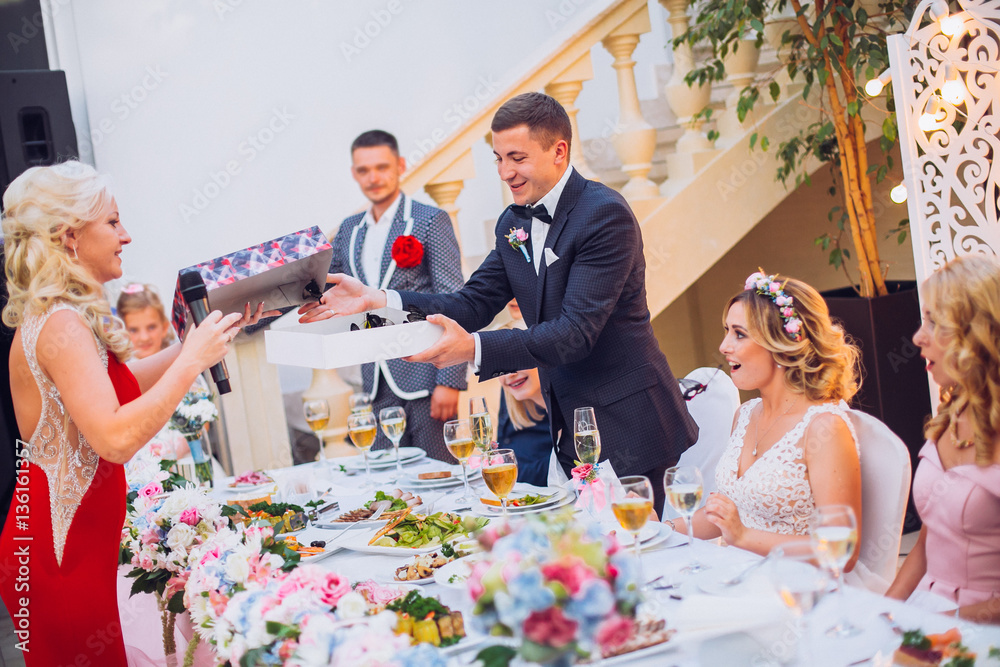 Newlyweds get an original gift butterfly from mother. Shocked and smiling bride. Groom emotions.