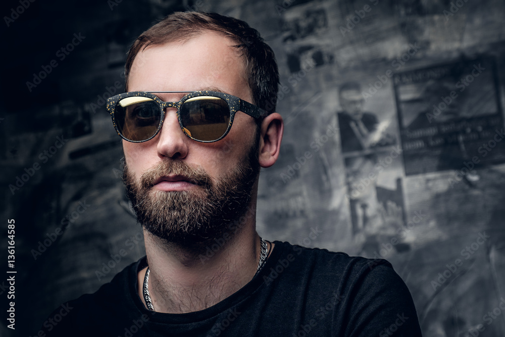 A man in sunglasses with tattoo on his arm.